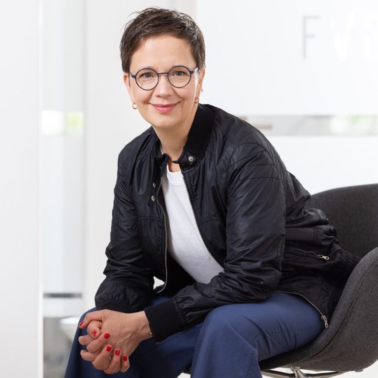 Das Bild zeigt Anika Franke, wie sie auf einem Stuhl sitzt und in die Kamera lächelt.