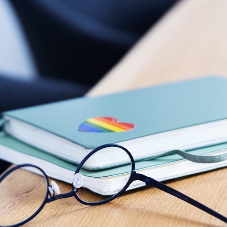 Notizen und Vielfalt Das Bild zeigt die Brille von Anika Franke und zwei ihrer typischen Notizbücher, mit denen sie arbeitet Auf dem oberen ein LGBTQ-Herz.